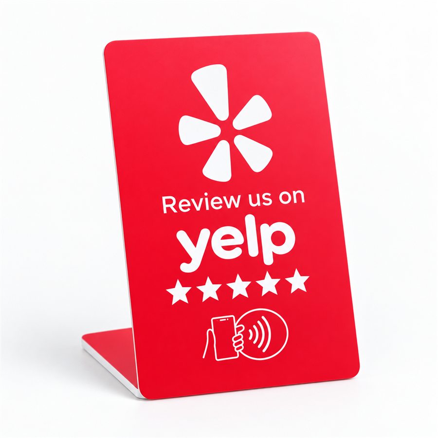 A red NFC counter stand reading Review us on Yelp, standing on its own folded base.